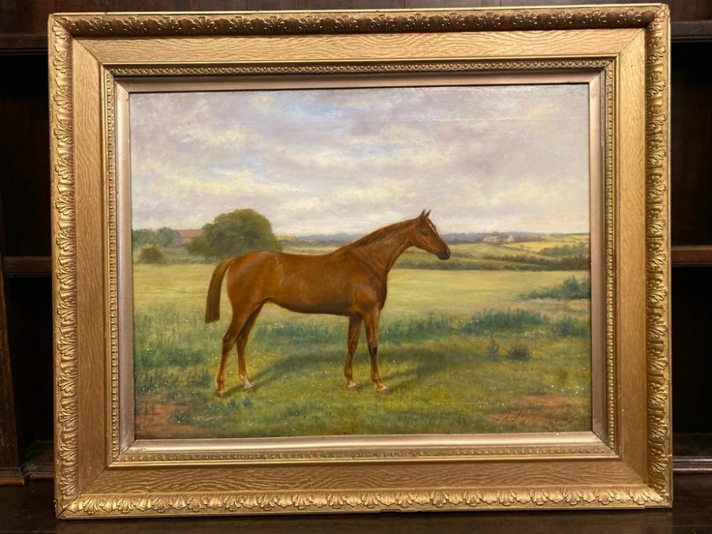 A 19th-century oil painting depicting a chestnut horse in profile standing in an open grassy field, enclosed within a moulded giltwood frame.