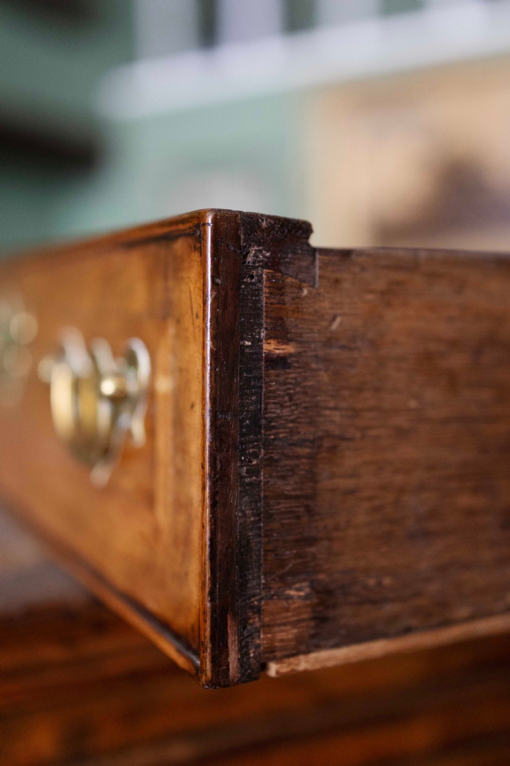 An early 18th-century walnut chest on stand with multiple crossbanded drawers, brass handles, a scalloped apron, and cabriole legs. View III