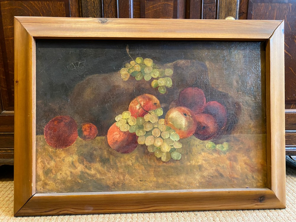 A framed oil painting depicting green grapes and red apples arranged on a tabletop against a dark background.