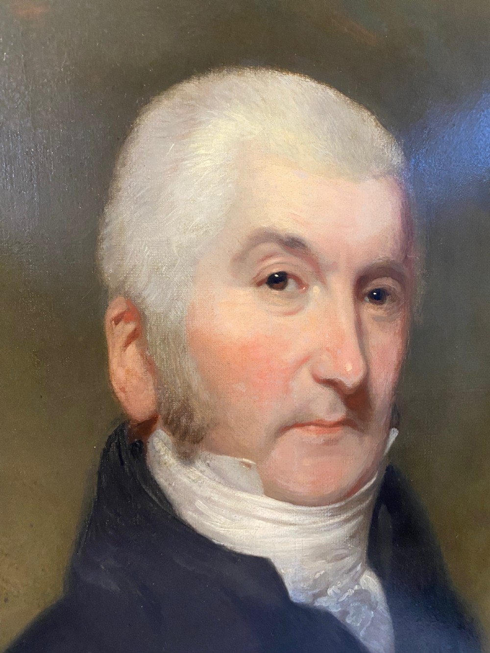 An 18th-century oil portrait painting depicting a gentleman wearing a dark coat and white cravat set in a gilt moulding frame. View II