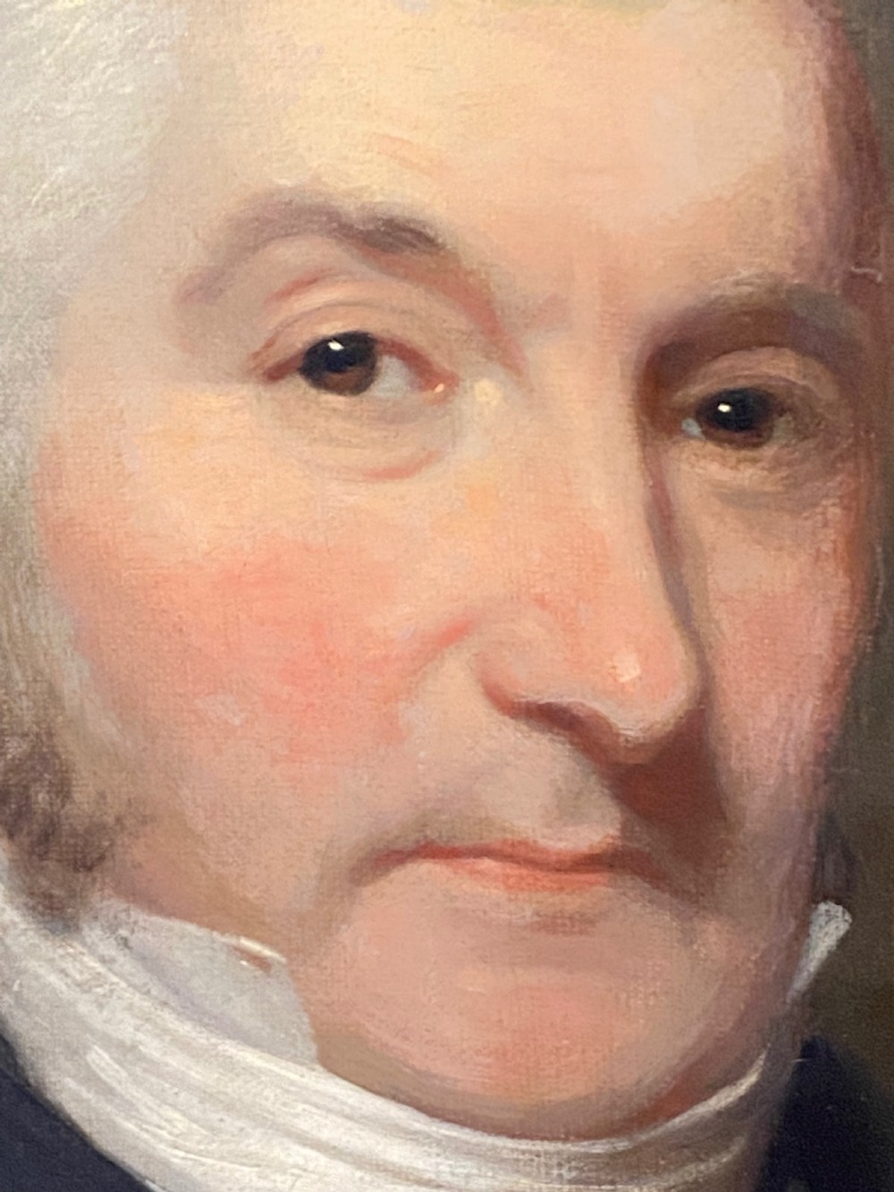 An 18th-century oil portrait painting depicting a gentleman wearing a dark coat and white cravat set in a gilt moulding frame. View IV