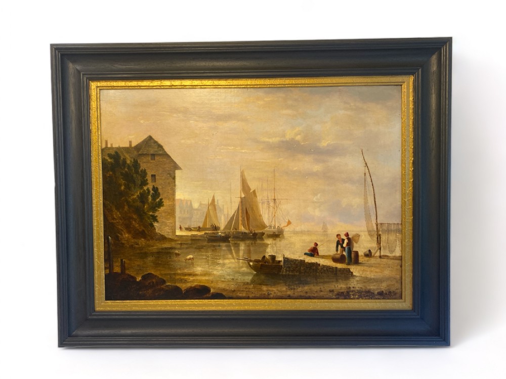An early 19th-century marine oil painting depicting sailboats and fishermen in a harbour under a golden sky, set within a dark moulding frame with a gold slip.