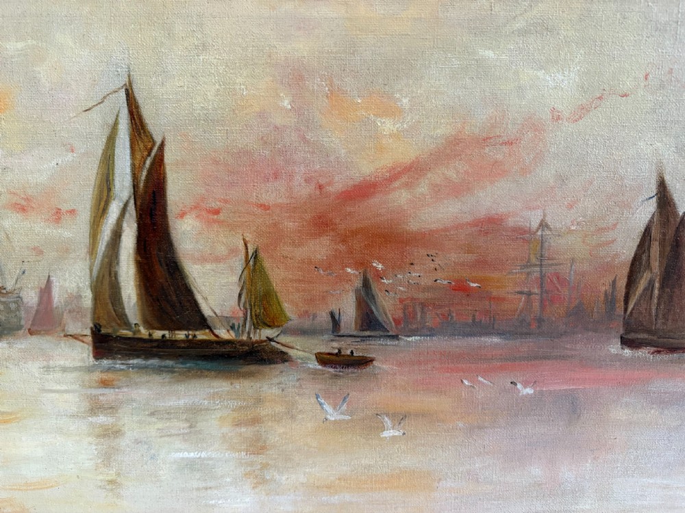 An Edwardian oil painting on canvas depicting sailing ships on calm water at sunset, set in a gold gilt frame. View V