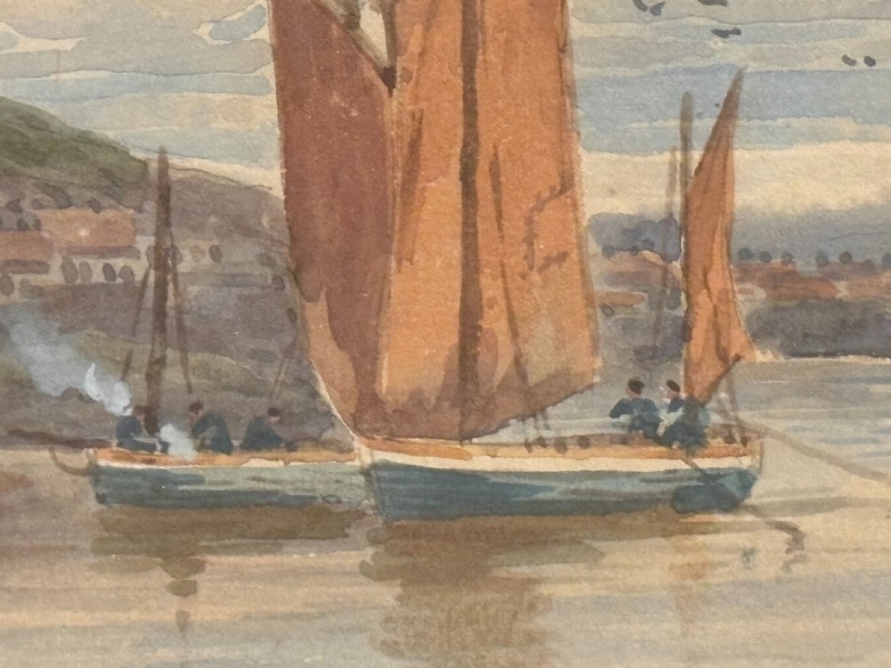 An Edwardian watercolour painting depicting fishing boats with reddish-brown sails in Whitby harbour, enclosed in a carved gilt frame. View VI