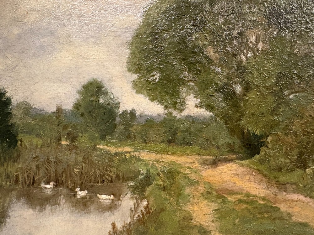 An oil painting depicting a rural landscape with geese swimming in a pond beside a dirt path under a large leafy tree, set in a carved gilt frame. View IV
