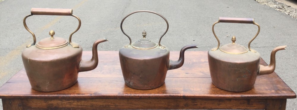A set of three 19th-century Victorian copper tea kettles with brass handles displayed side by side. View II