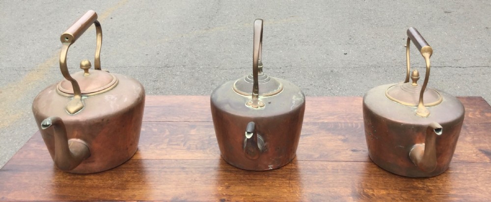 A set of three 19th-century Victorian copper tea kettles with brass handles displayed side by side. View IV