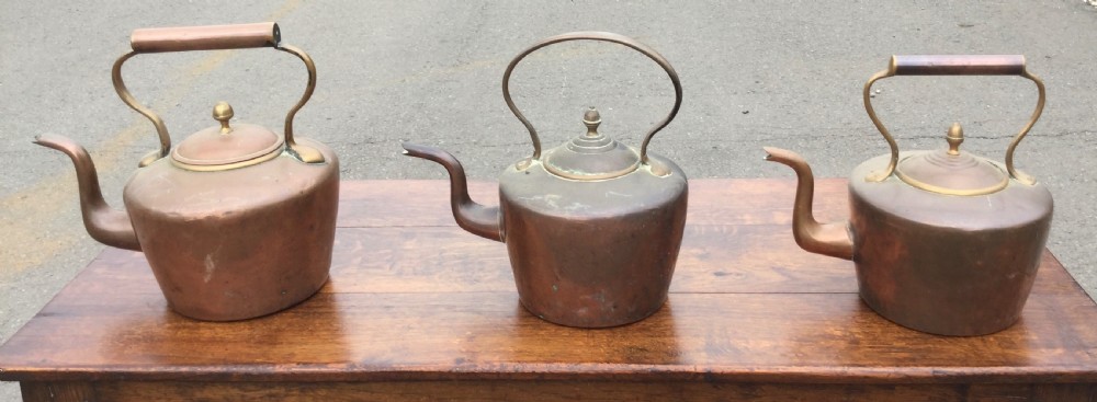 A set of three 19th-century Victorian copper tea kettles with brass handles displayed side by side. View V