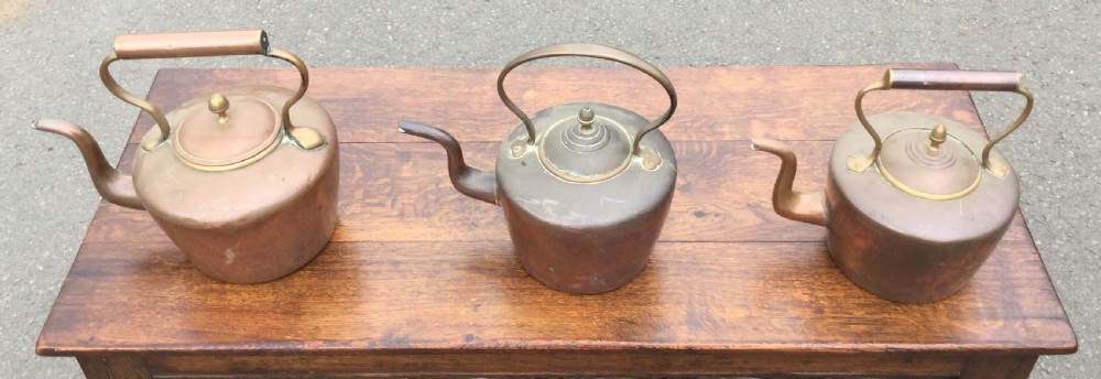 A set of three 19th-century Victorian copper tea kettles with brass handles displayed side by side. View VI