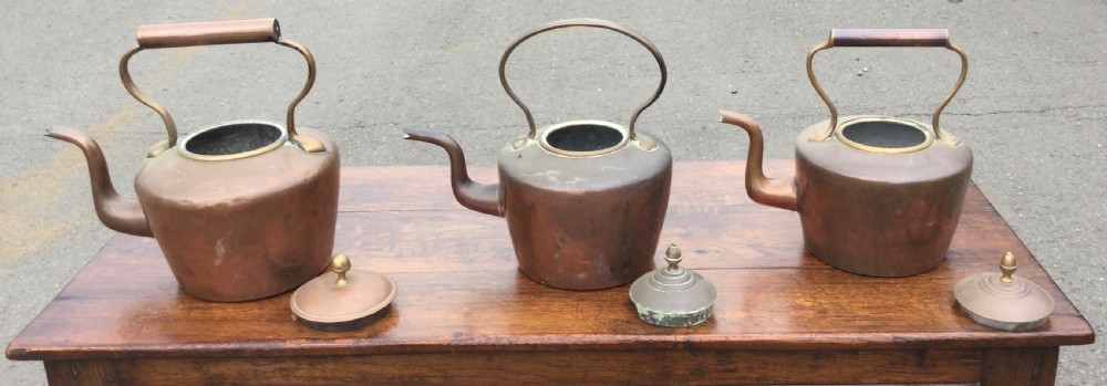A set of three 19th-century Victorian copper tea kettles with brass handles displayed side by side. View VII