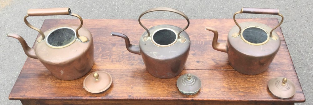 A set of three 19th-century Victorian copper tea kettles with brass handles displayed side by side. View VIII