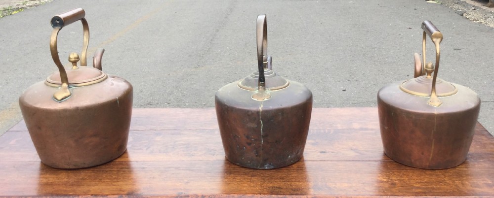 A set of three 19th-century Victorian copper tea kettles with brass handles displayed side by side. View IX