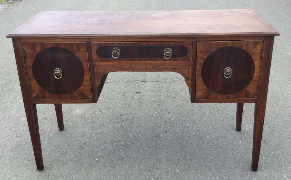 A Georgian mahogany sideboard featuring circular inlaid cupboard doors, a central drawer with brass ring handles, and tapered legs.