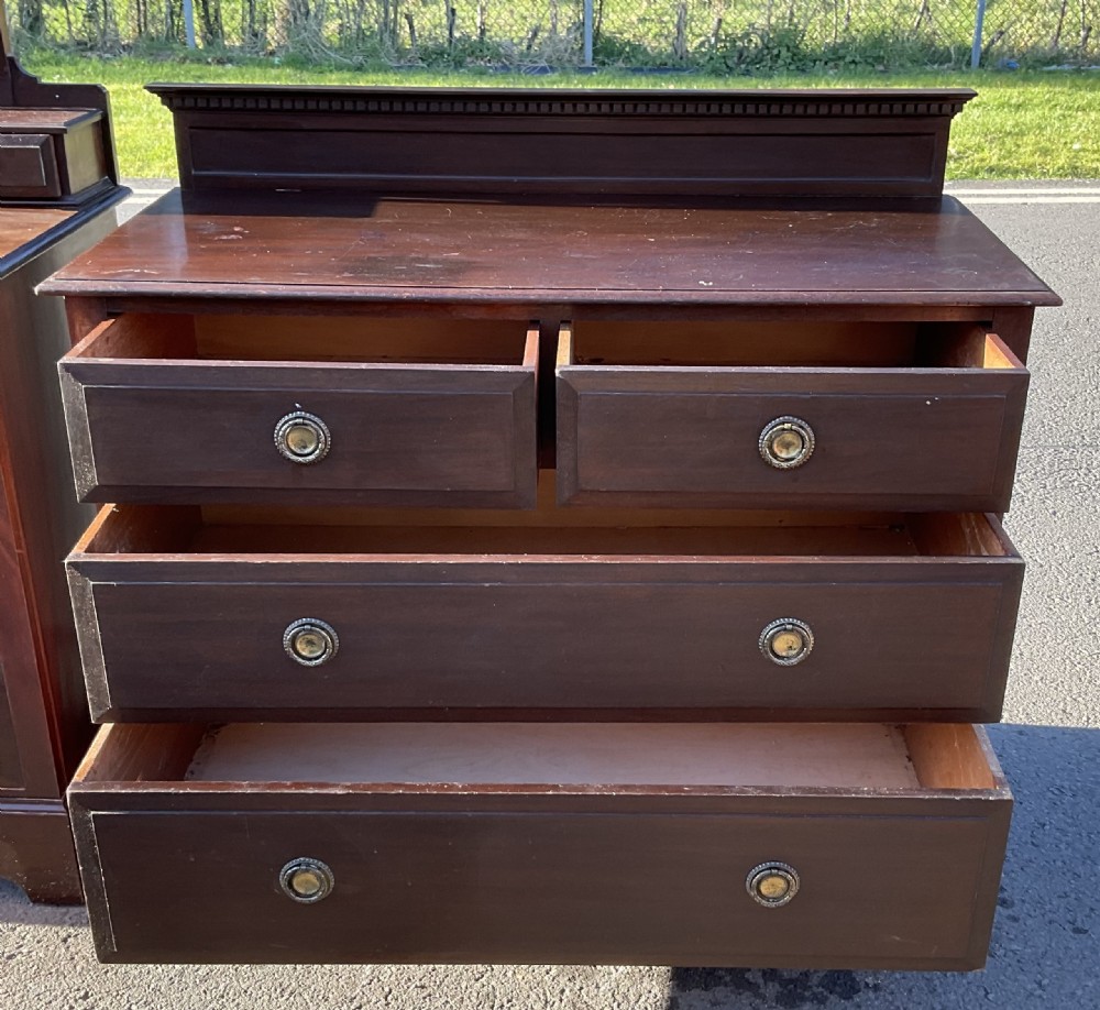 A pair of dark Edwardian mahogany furniture pieces featuring a dressing chest with a tilting mirror alongside a matching chest of drawers. View IV