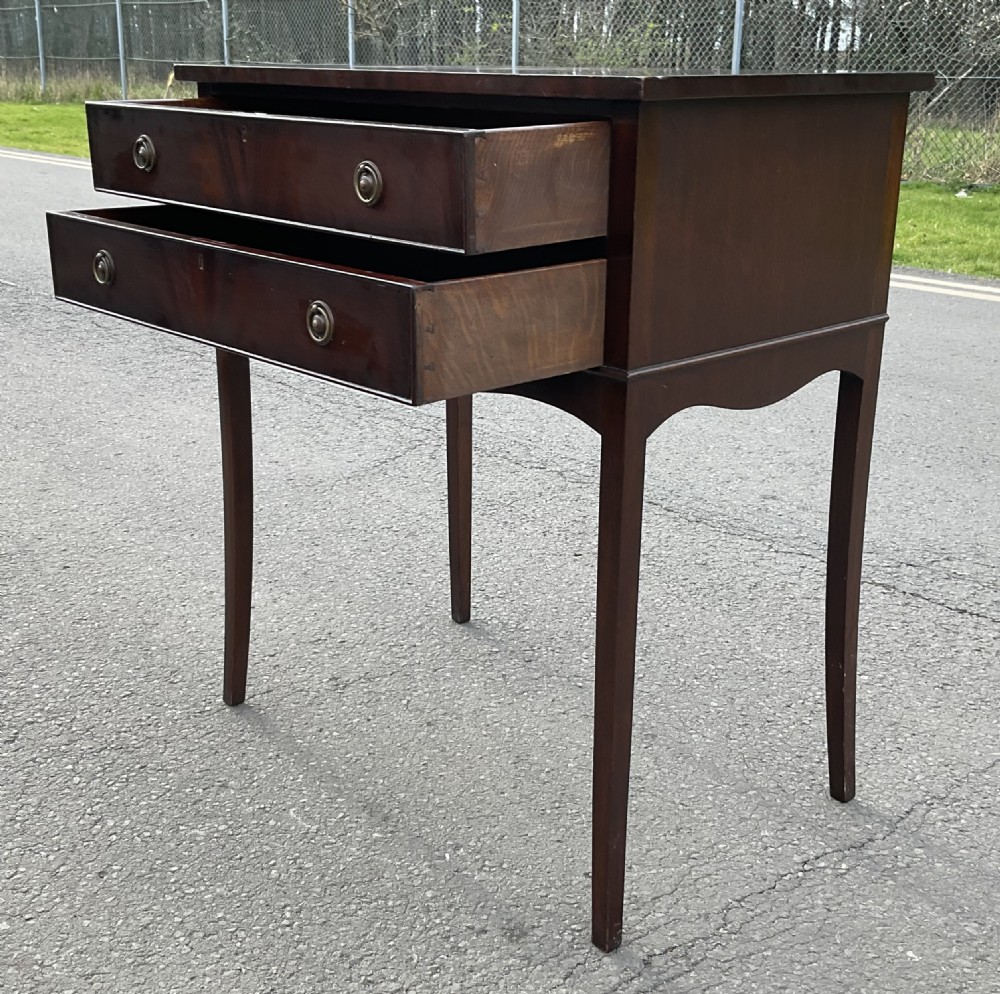 An Edwardian mahogany two-drawer chest featuring brass ring drop handles, flame mahogany veneer, and long tapered legs. View VI