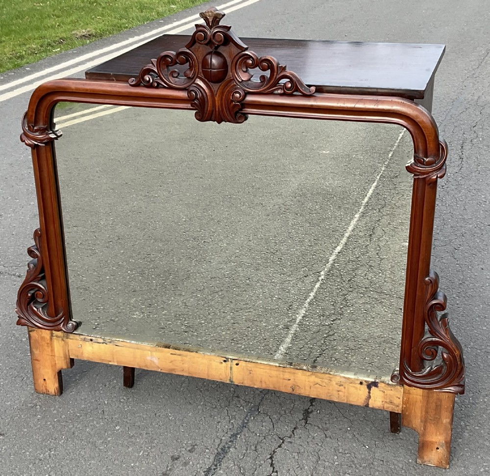 A Victorian mahogany overmantel mirror featuring a carved central crest with scrollwork detail and side brackets. View II