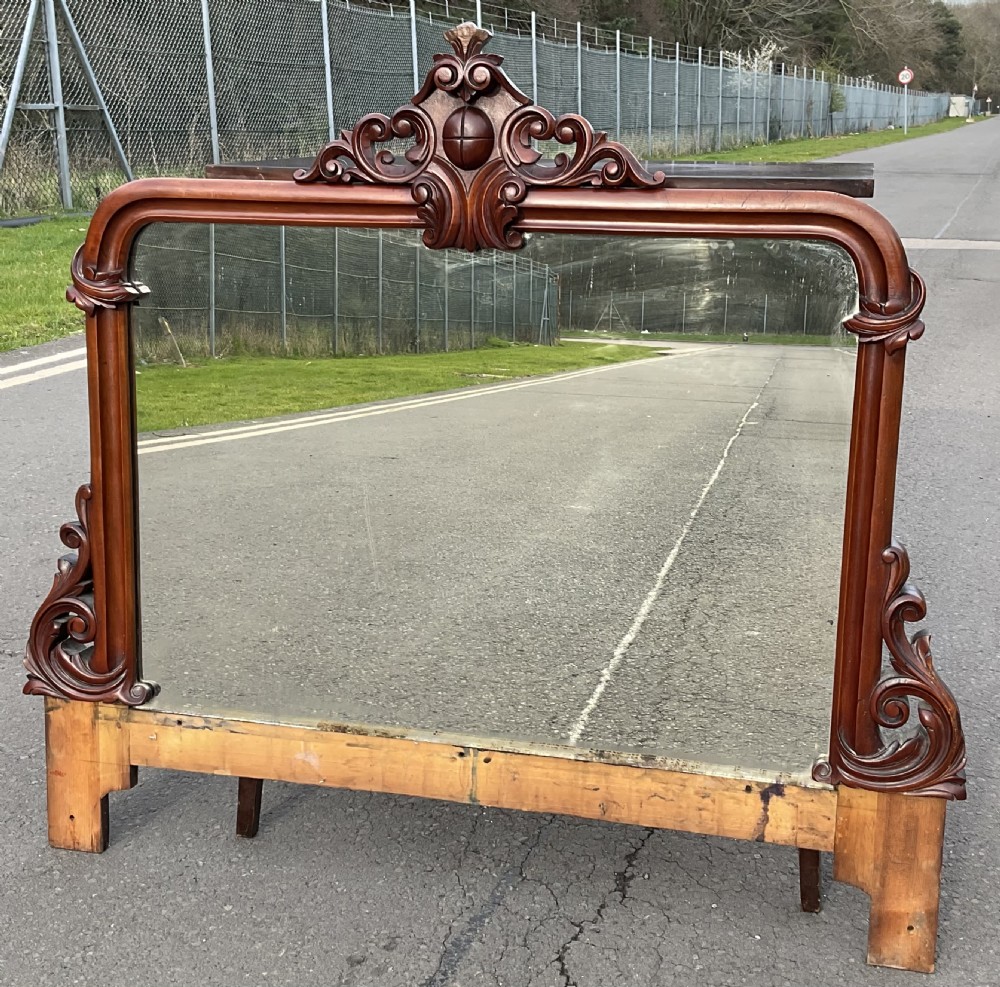 A Victorian mahogany overmantel mirror featuring a carved central crest with scrollwork detail and side brackets. View III