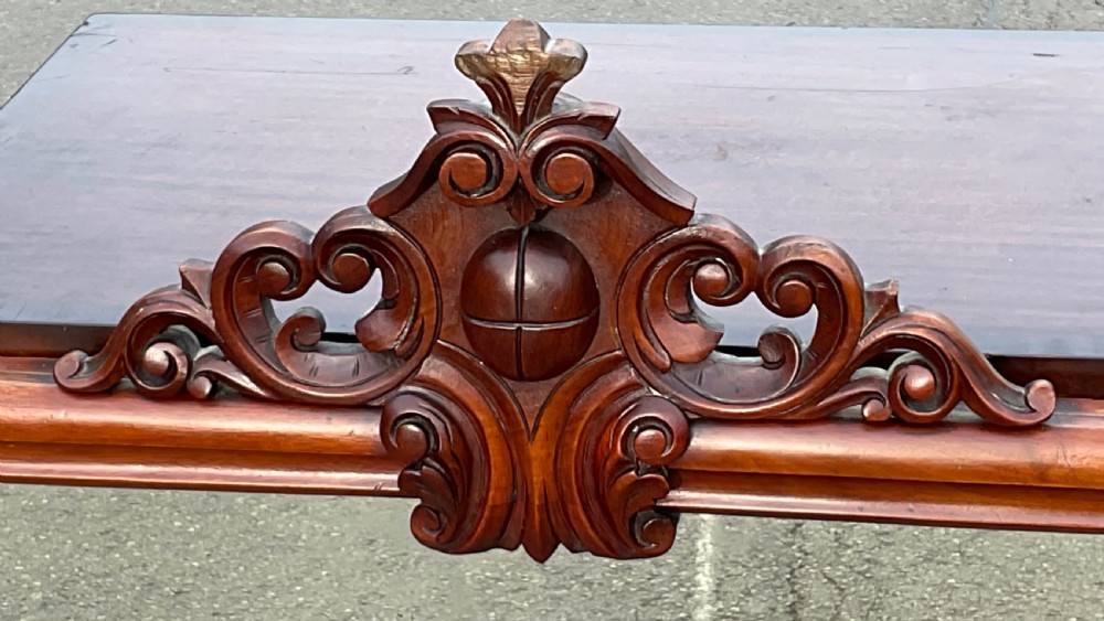 A Victorian mahogany overmantel mirror featuring a carved central crest with scrollwork detail and side brackets. View V