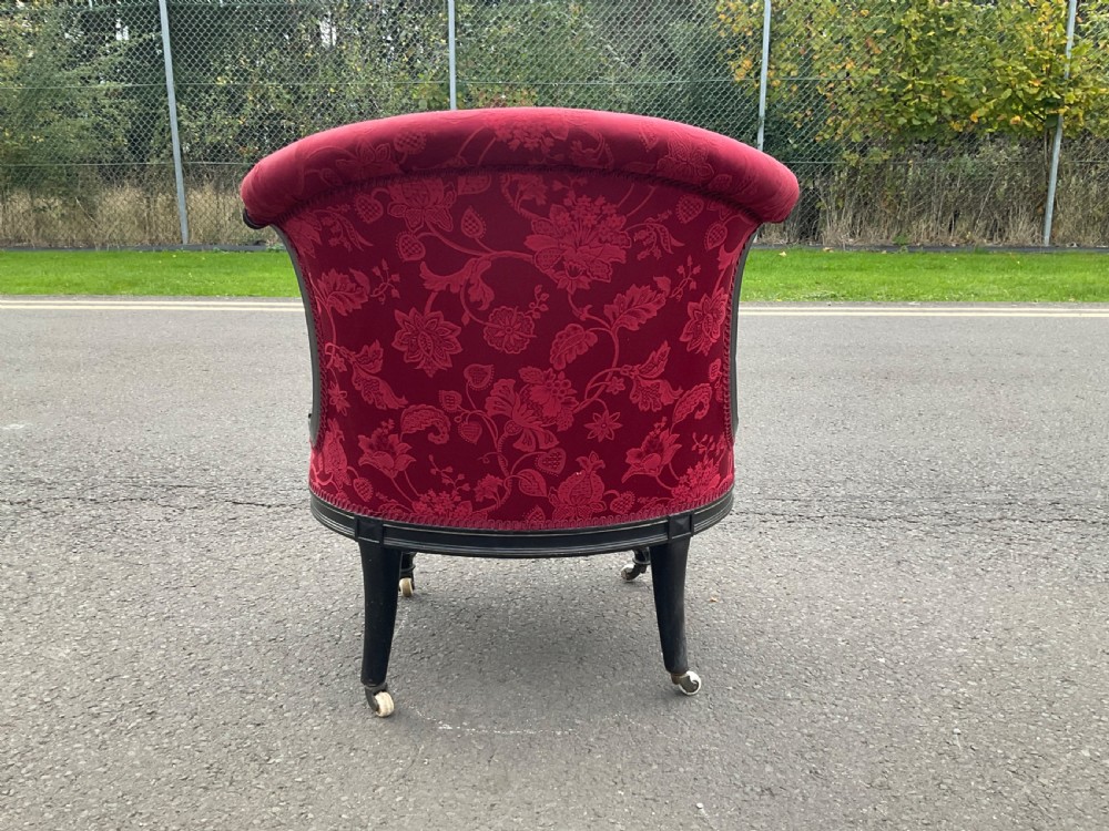 Victorian Aesthetic Movement nursing chair featuring a black ebonised wood frame, turned legs on casters, and red damask upholstery. View VI