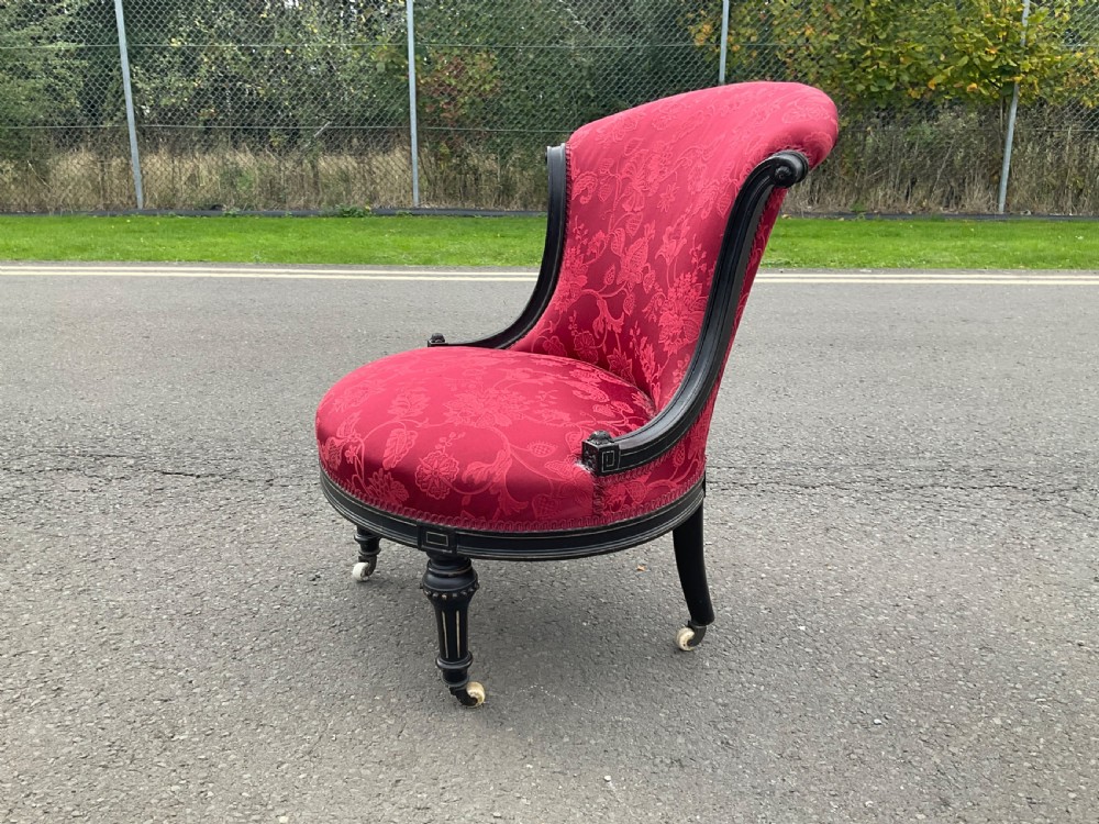 Victorian Aesthetic Movement nursing chair featuring a black ebonised wood frame, turned legs on casters, and red damask upholstery. View VII