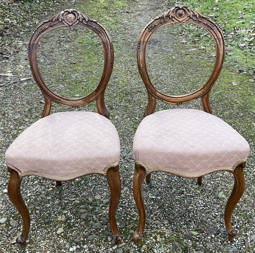 A pair of Victorian carved walnut balloon back dining chairs featuring padded pink fabric seats and cabriole legs. View II