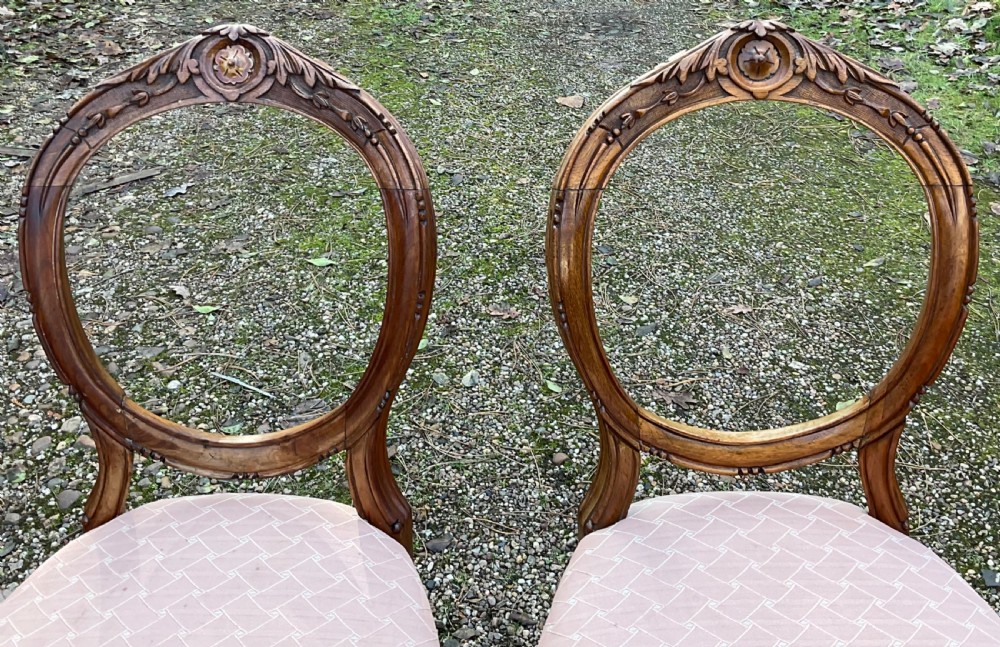 A pair of Victorian carved walnut balloon back dining chairs featuring padded pink fabric seats and cabriole legs. View IV