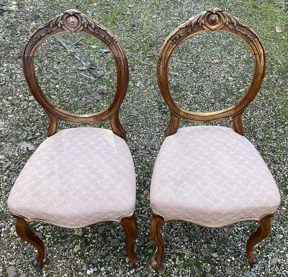 A pair of Victorian carved walnut balloon back dining chairs featuring padded pink fabric seats and cabriole legs. View V