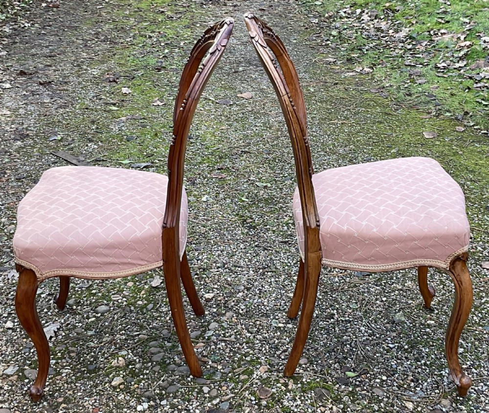 A pair of Victorian carved walnut balloon back dining chairs featuring padded pink fabric seats and cabriole legs. View VI