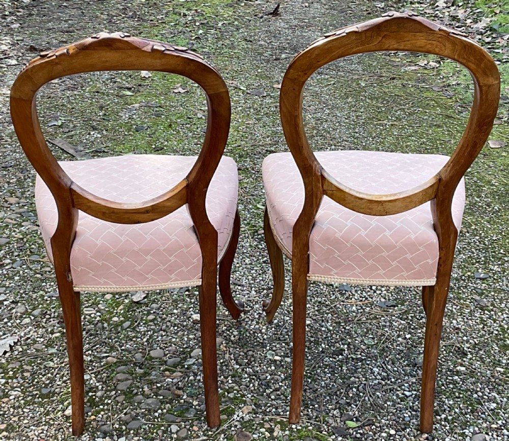 A pair of Victorian carved walnut balloon back dining chairs featuring padded pink fabric seats and cabriole legs. View VIII