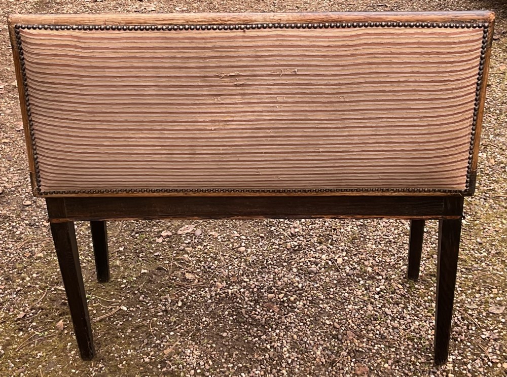 An Edwardian dark mahogany duet piano stool featuring four tapered legs and a padded striped fabric seat trimmed with brass studs. View V