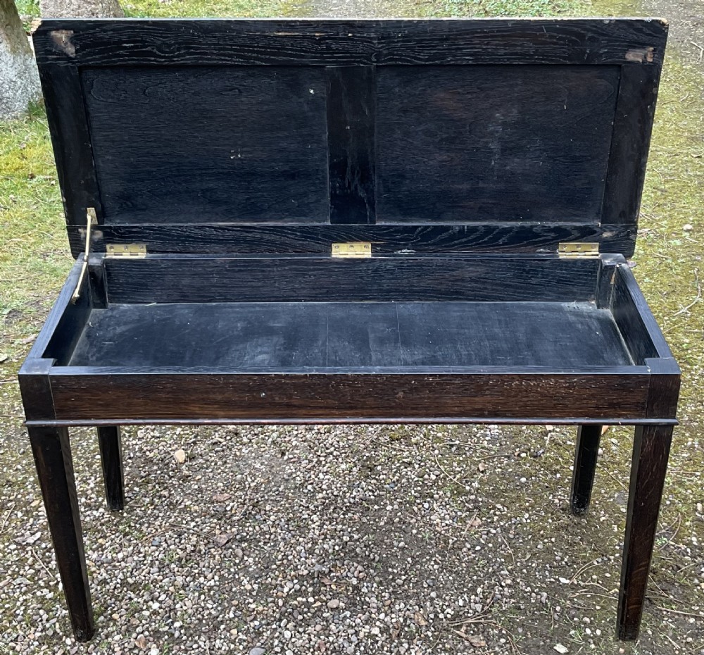 An Edwardian dark mahogany duet piano stool featuring four tapered legs and a padded striped fabric seat trimmed with brass studs. View VI