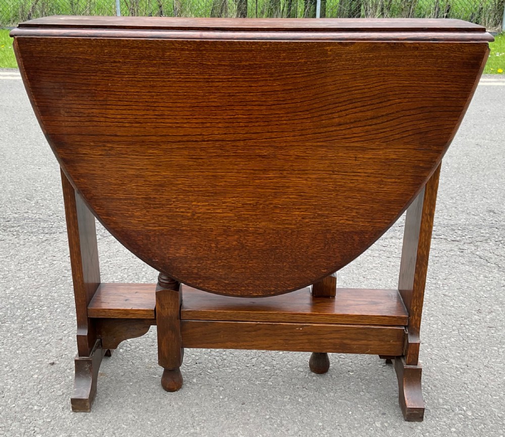 A solid oak drop-leaf dining table shown in a folded compact position. View II