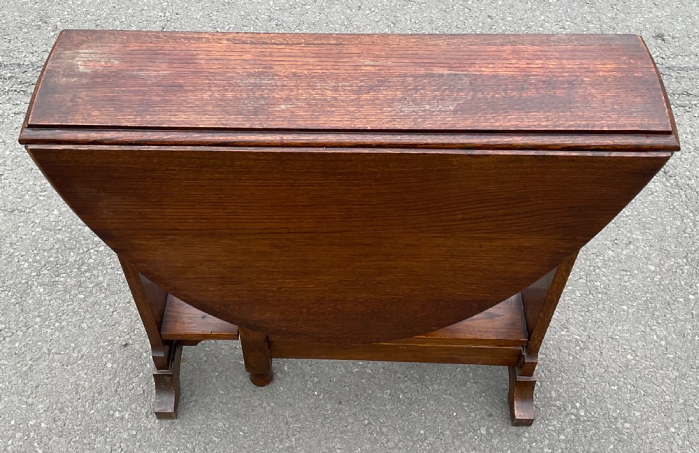 A solid oak drop-leaf dining table shown in a folded compact position. View III