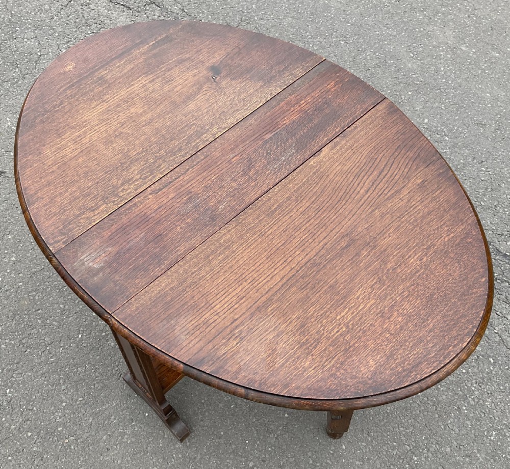 A solid oak drop-leaf dining table shown in a folded compact position. View VI