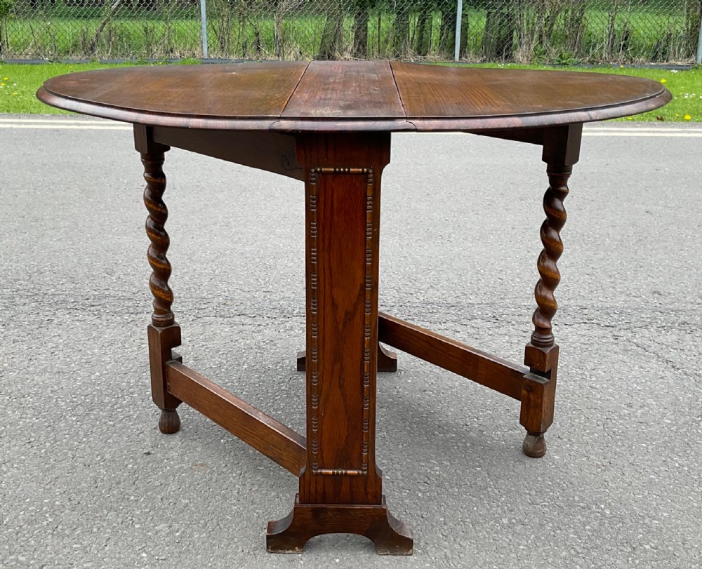 A solid oak drop-leaf dining table shown in a folded compact position. View VIII