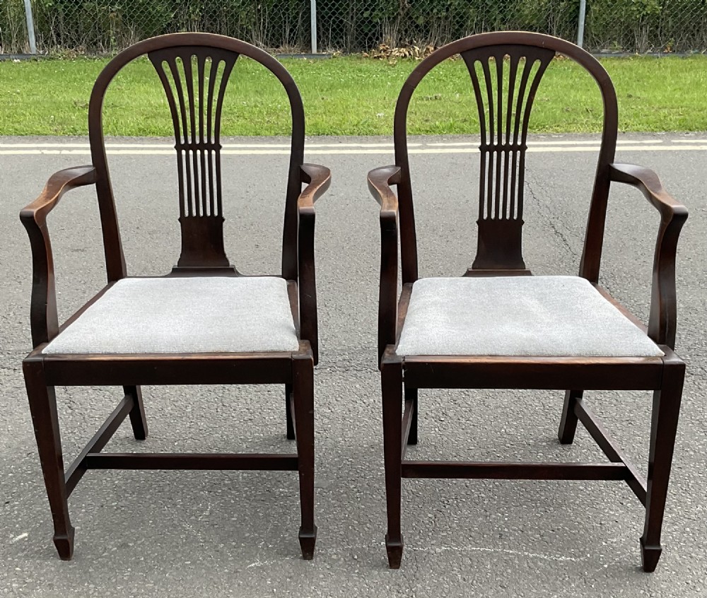 A pair of dark mahogany Georgian style carver armchairs featuring pierced back splats, curved armrests, and light grey upholstered seats.
