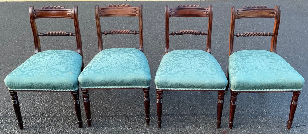 A set of four Georgian mahogany dining chairs featuring carved top rails, rope-twist crossbars, and light green damask upholstered seats.