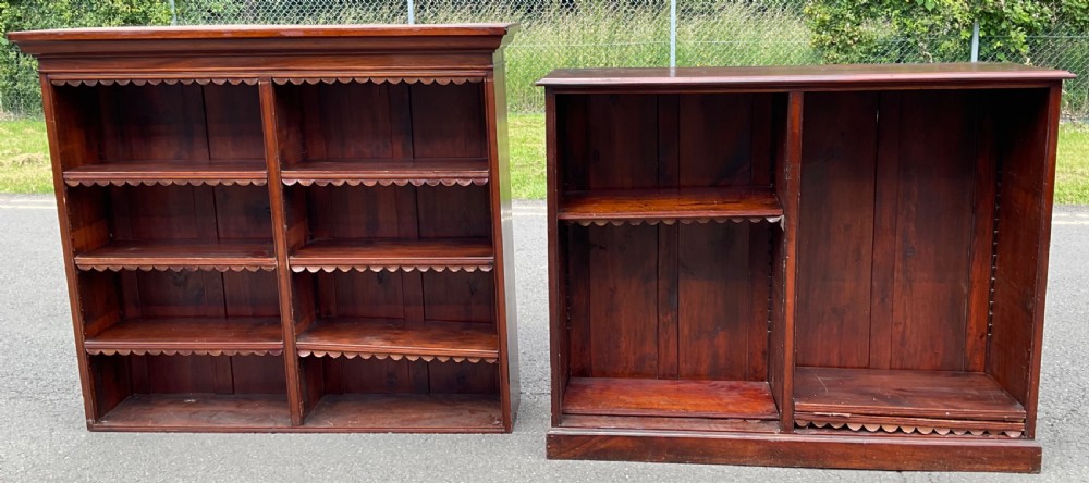 A pair of Victorian mahogany open bookcases featuring scalloped shelf trimming and twin-section wooden compartments.