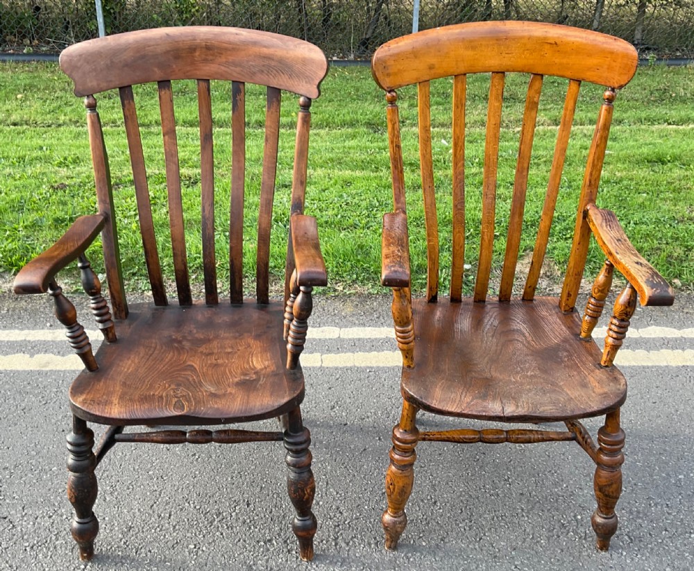 A pair of antique wooden Windsor armchairs with spindle backs, shaped seats, turned legs, and stretchers, finished in a warm brown timber polish.