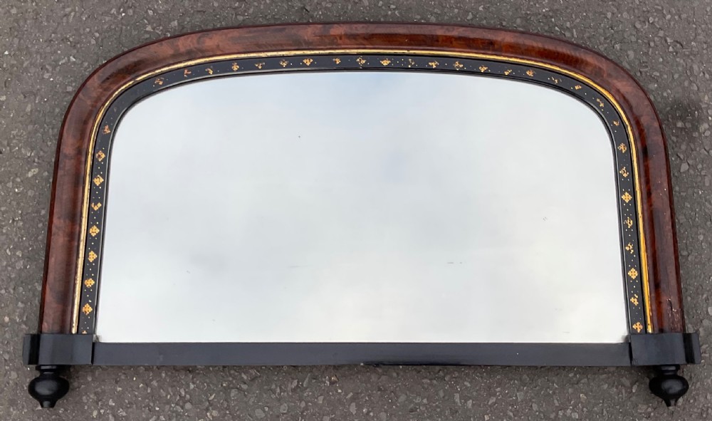 An arched antique Aesthetic Movement overmantel mirror featuring a burr walnut frame with an inner ebonised border decorated with incised gilt details.
