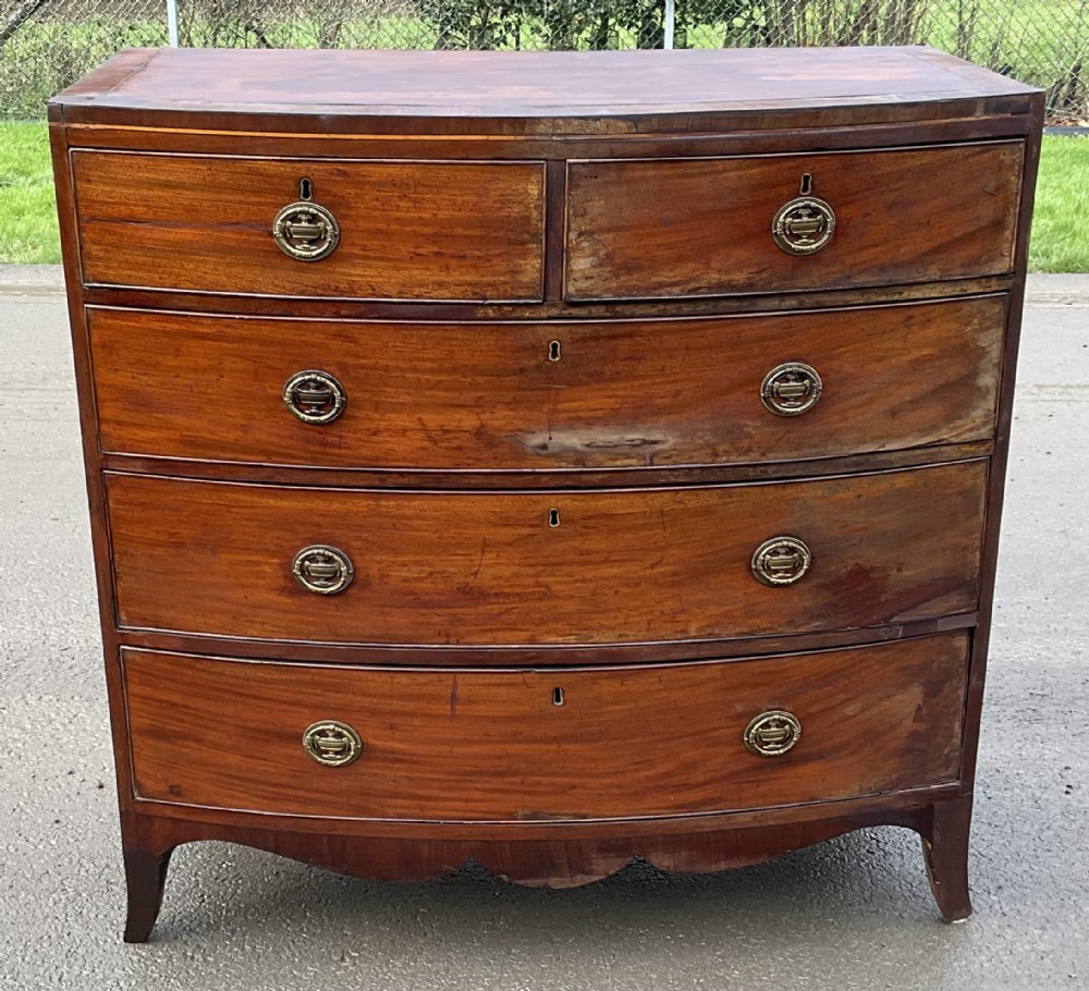 A Georgian mahogany bowfront chest of drawers featuring two short over three long graduated drawers with brass oval handles and splay bracket feet.