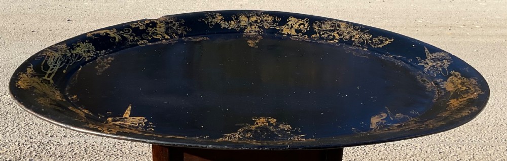 A large Georgian oval black lacquered tray featuring intricate gilt chinoiserie border details.