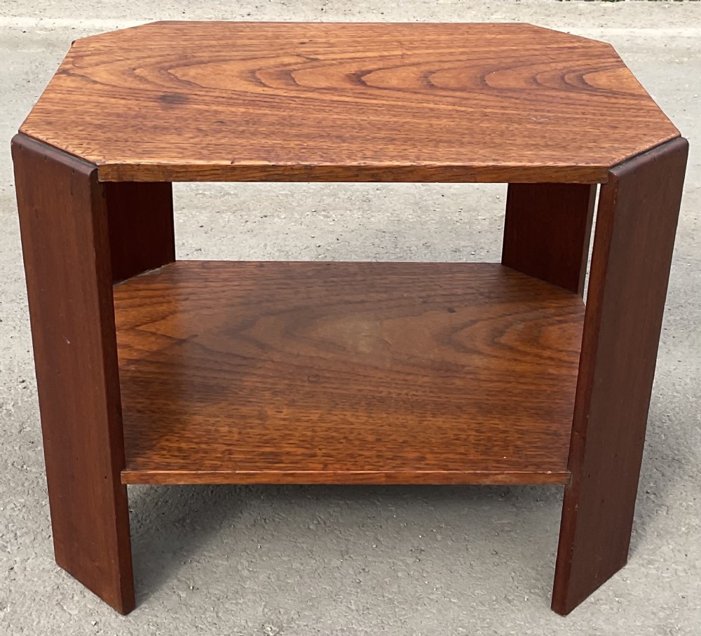 An Art Deco warm brown oak low coffee table featuring an octagonal top, a matching lower shelf, and broad angled slab legs.