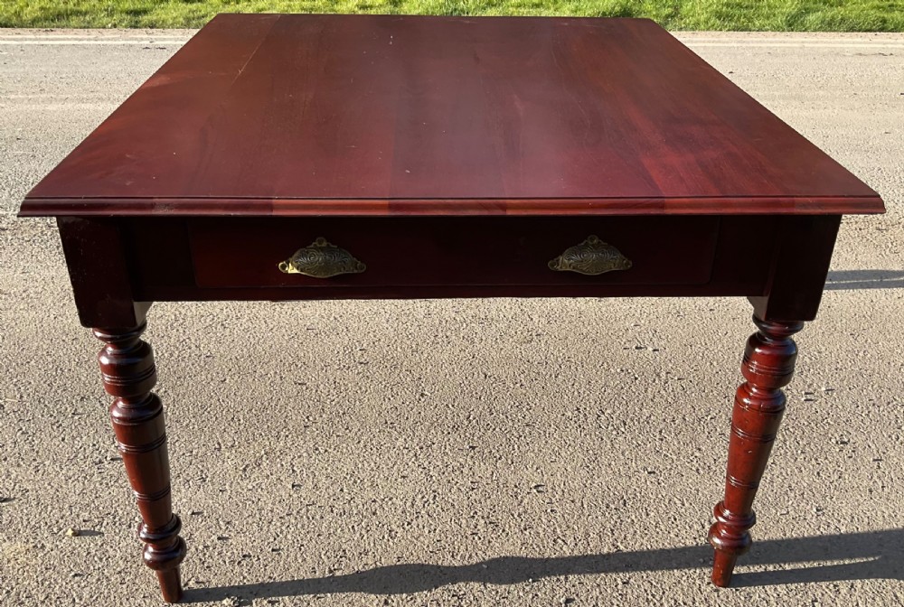 A rectangular Victorian mahogany dining table featuring turned legs and a front frieze drawer with two ornate brass handles.