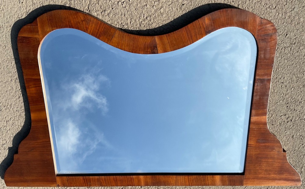 A wide walnut overmantel mirror featuring a contoured upper frame and a bevelled glass edge.