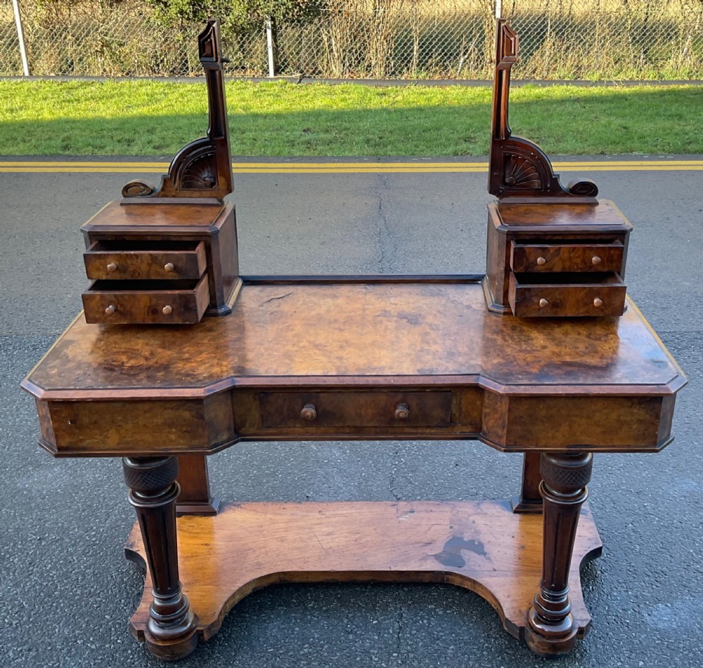 A Victorian burr walnut dressing table featuring a central adjustable rectangular mirror, tiered side drawers, turned front legs, and a shaped lower shelf. View VI