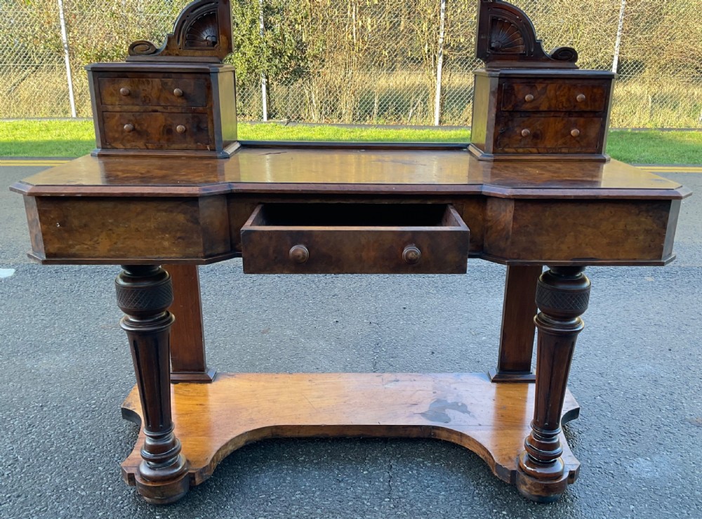 A Victorian burr walnut dressing table featuring a central adjustable rectangular mirror, tiered side drawers, turned front legs, and a shaped lower shelf. View VII