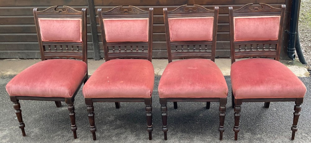 A set of four Edwardian walnut dining chairs upholstered in dusty rose pink velvet with carved cresting rails and turned front legs.