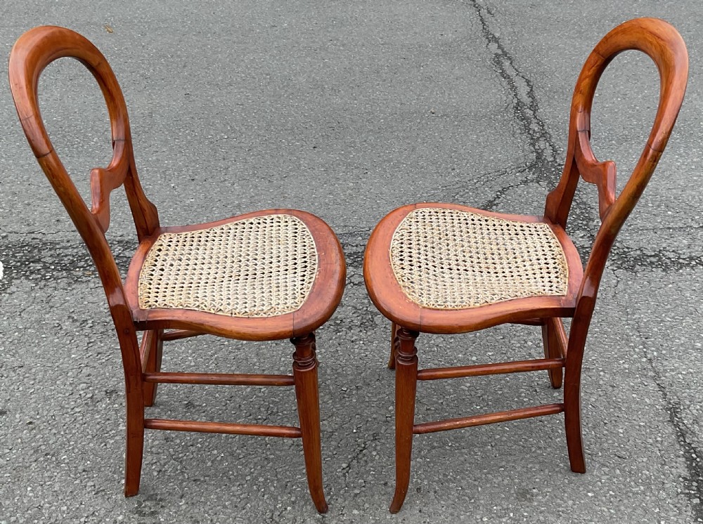 A pair of Victorian mahogany balloon-back side chairs with woven cane seats and turned legs. View II