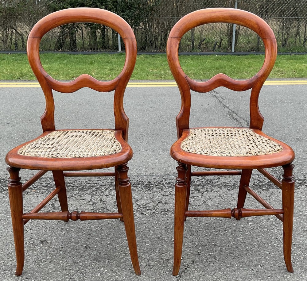 A pair of Victorian mahogany balloon-back side chairs with woven cane seats and turned legs. View VI